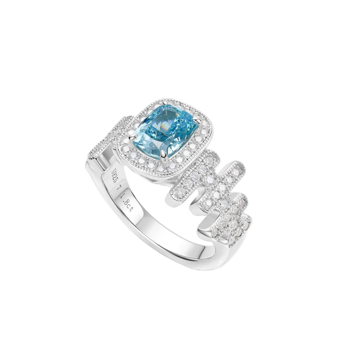 The Gem Vivi Cadence Cascade Ring showcases a cushion-cut lab-created blue aquamarine in 18k white gold, accented by sparkling white stones on a unique wavy band.
