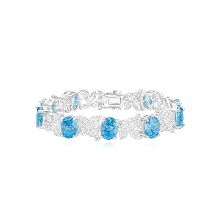 The Gem Vivi Aquamarine Oval Leaf Tennis Bracelet is crafted in 18k white gold with oval ocean blue gemstones and clear crystal accents in a delicate leaf-inspired floral design.