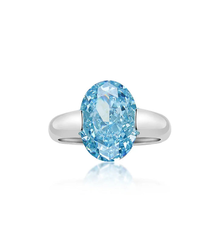 The Gem Vivi Crystal Blue Drop Ring in 18k white gold features a large oval blue gemstone set on a simple band, shown against a white background.