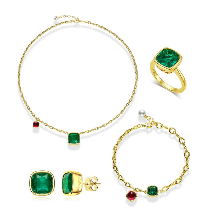 A gold jewelry set with green gemstones and the Gem Vivi Chloe Duo Charm Bracelet in 18k Yellow Gold, featuring a necklace, ring, bracelet, and earrings, elegantly displayed on a white background.