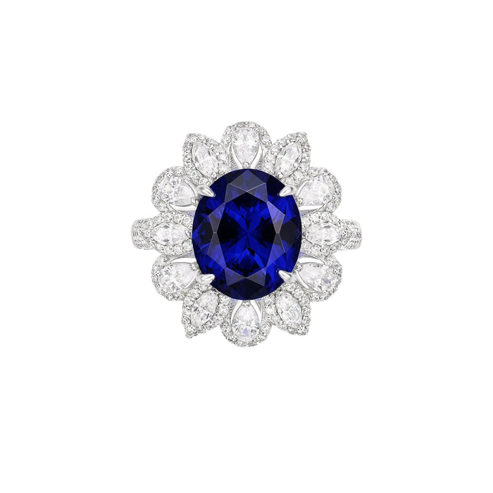 The Midnight Glow Halo Ring by Gem Vivi features an oval-cut sapphire center, encircled by pear-shaped and round diamonds, set in luminous 18k white gold.