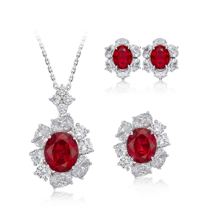 The Cynthia Ruby Spark Pendant Necklace by Gem Vivi features an oval-cut lab-created ruby with clear stones in 18k white gold, and is part of a matching jewelry set with earrings and a ring.