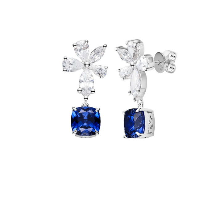 The Blue Sapphire Twilight Petal Drop Earrings by Gem Vivi feature flower-shaped white gemstones and dangling cushion-cut sapphires, all set in 18k white gold.