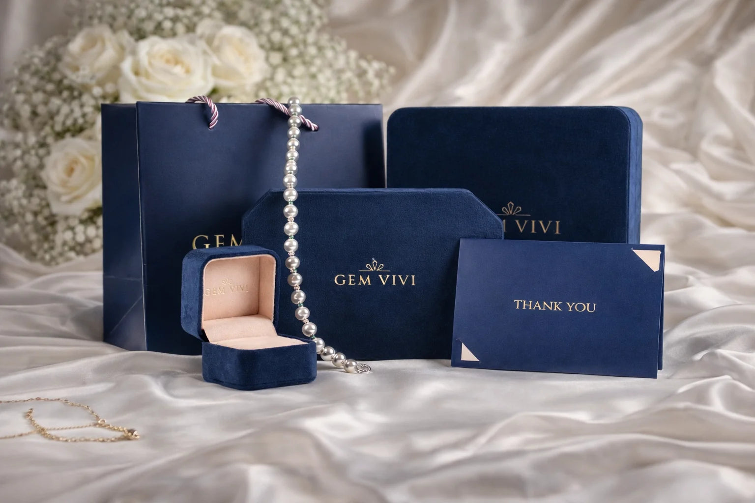 Gem Vivi signature navy packaging with gift box, thank you card, and jewelry pouch on satin backdrop