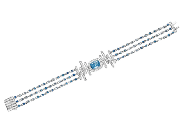 The Cadence Cascade Bracelet by Gem Vivi features three gemstone strands with a central cushion-cut blue gemstone, geometric diamond accents, and a lustrous 18k white gold setting.