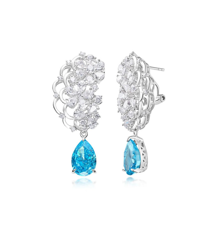 The Azure Petal Waterfall Earrings by Gem Vivi feature clusters of clear gemstones and a blue teardrop stone, crafted in 18k white gold and hanging elegantly on a white background.
