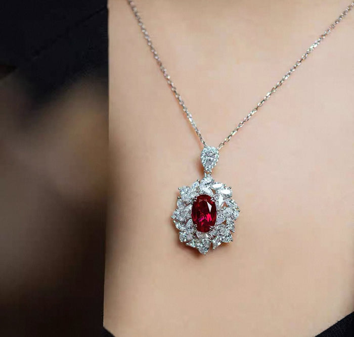 The Blossom Ruby Pendant Necklace by Gem Vivi features a large oval lab-created ruby surrounded by clear crystals, set in 18k white gold for an elegant look.
