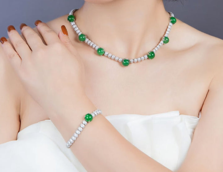 A woman in a white strapless top models Gem Vivi’s Chalcedony Cabochon Ring, her hand resting on her shoulder, highlighting the elegant green stone set in 18k white gold.