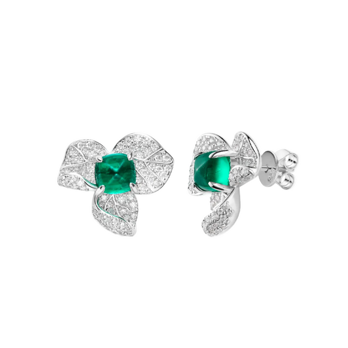 The Gem Vivi Emerald Leaf bloom Earrings are sterling silver studs with leaf-shaped designs, featuring marquise-cut green stones at the center and sparkling clear stone accents.