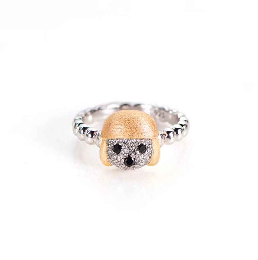 The Gem Vivi Dog In Golden Hat Ring features a silver band, an 18K yellow gold-colored textured head, and a face design accented with black and clear cubic zirconia for the eyes and mouth.