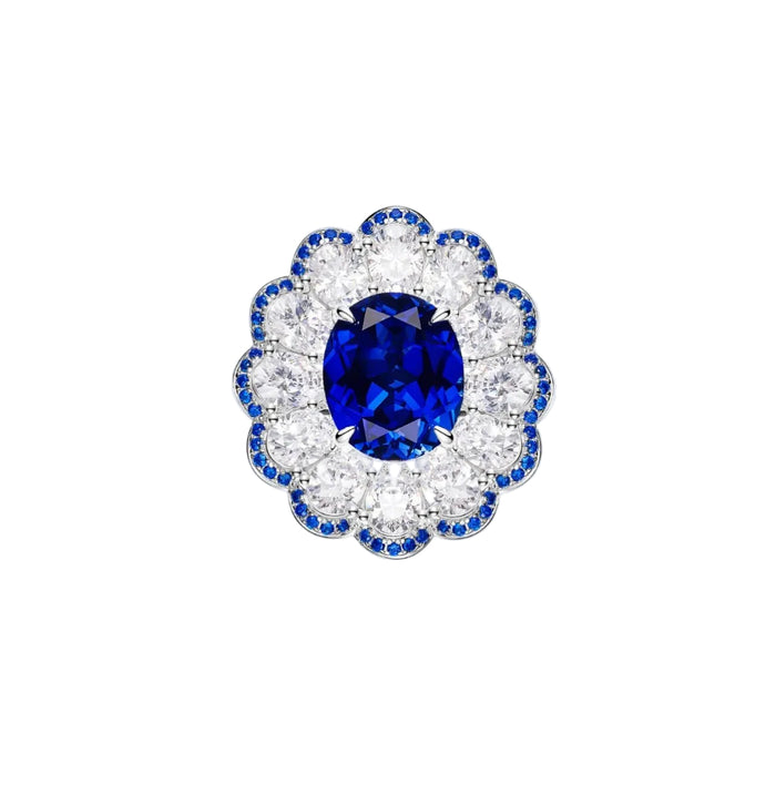 The Bloom Midnight Sapphire Ring by Gem Vivi showcases a large oval blue sapphire center set in 18k white gold, surrounded by round white diamonds and smaller blue stones in a floral-inspired design.