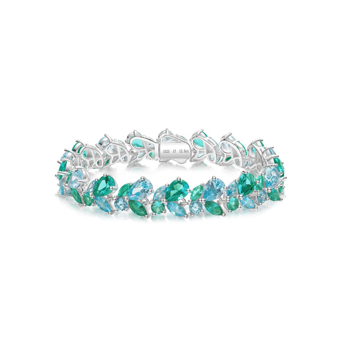 The Gem Vivi Ocean Prism Duo Bracelet features a secure clasp and leaf-shaped design with alternating blue and green gemstones, crafted in sterling silver with an 18k white gold finish.