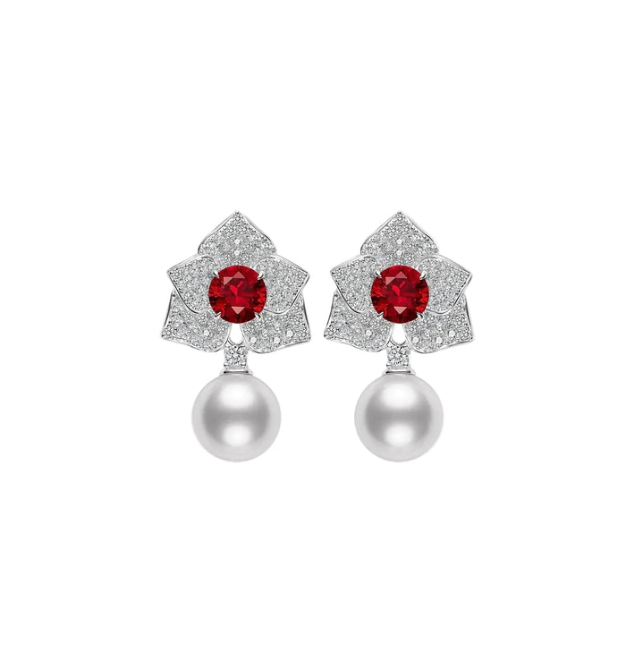 The Cascade Pearl Rosette Ruby Earring by Gem Vivi features lab ruby gemstones in a floral design with small clear stones and a single white pearl drop on each.