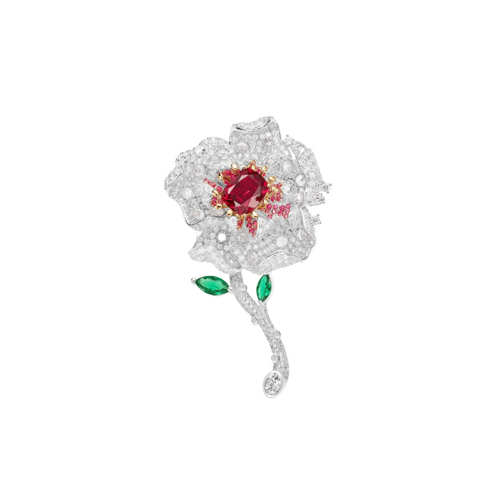 The Cherish Floral Brooch by Gem Vivi features a cushion cut ruby center, white gem petals, two green gemstone leaves, and an elegant 18k white gold stem.