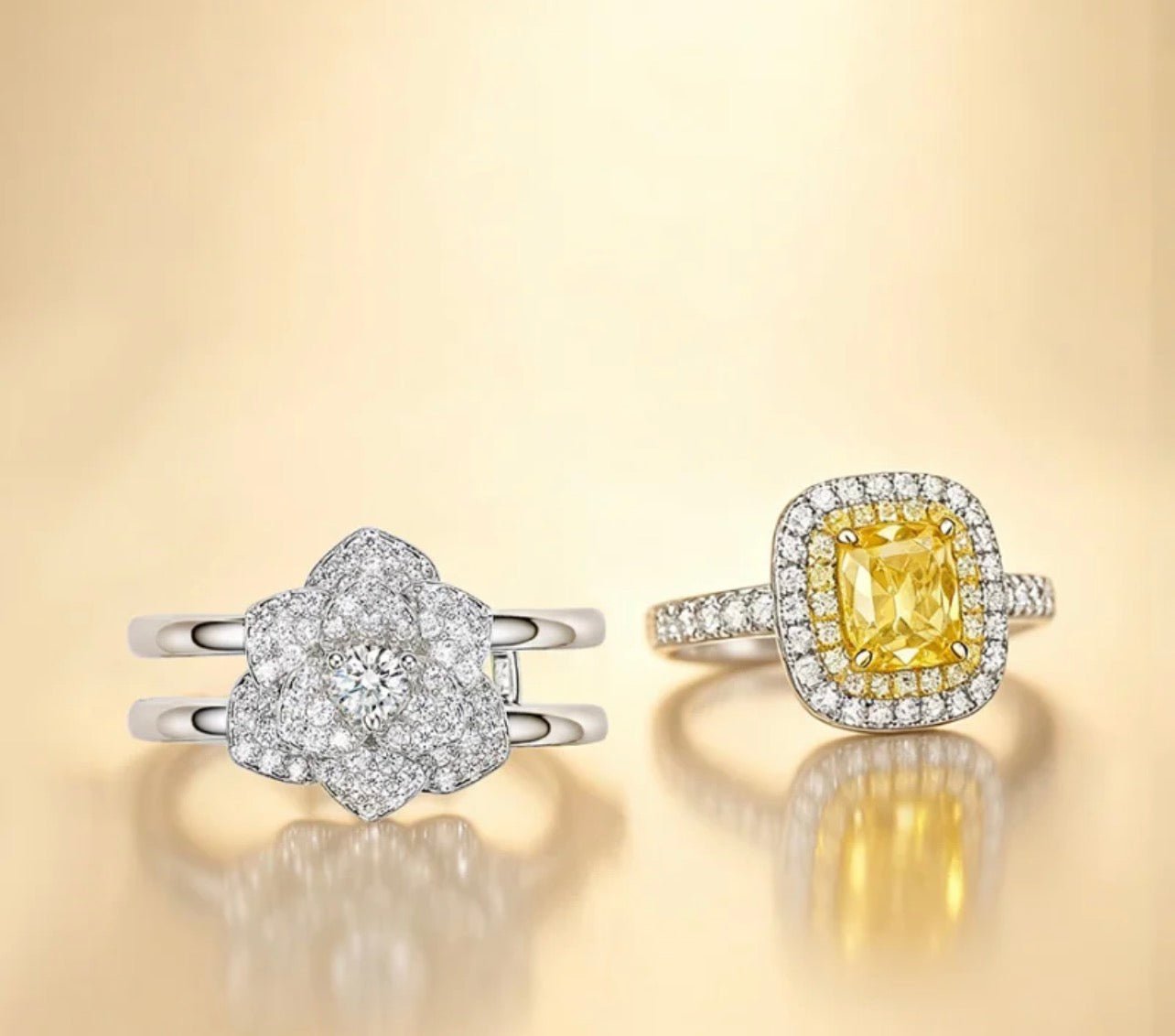 The Gem Vivi Petal Charm Ring Set features two rings: one with a petal motif and white diamonds, the other a yellow cushion-cut halo ring in 18k white gold adorned with sparkling diamonds.