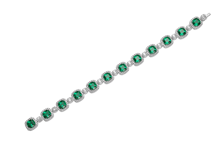 The Gem Vivi Emerald Candy Cube Cushion Bracelet showcases vibrant green gemstones, each bordered by clear accents, arranged in a row and elegantly displayed on a white background.
