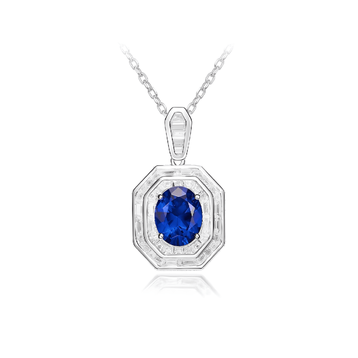 The Gem Vivi Blue Sapphire Halo Pendant Necklace features a large oval sapphire encircled by sparkling stones, displayed on a reflective white background.
