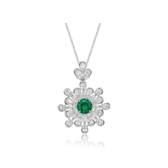 The Gem Vivi Emerald Snowflake Pendant Necklace features a lab-created emerald at the center of a snowflake design, accented with clear round stones on a silver chain.