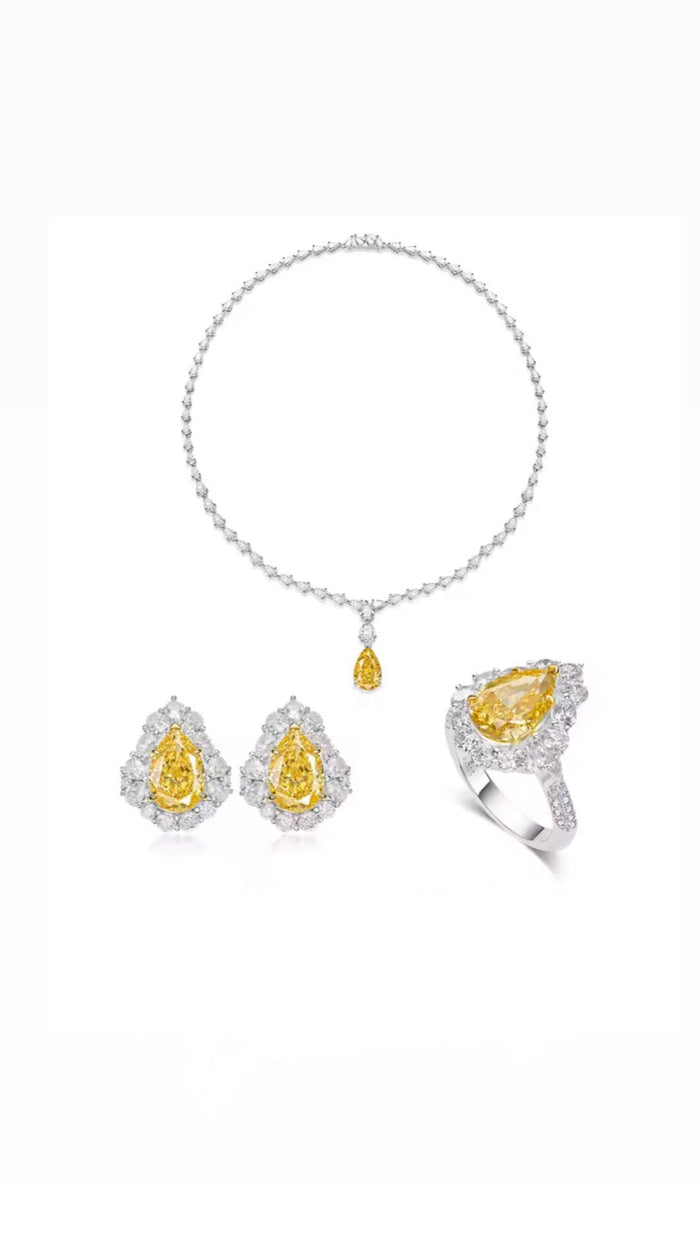 The Gem Vivi Canary Yellow Teardrop Statement Necklace features vivid yellow gemstones accented by clear stones in sterling silver, displayed on a white background.
